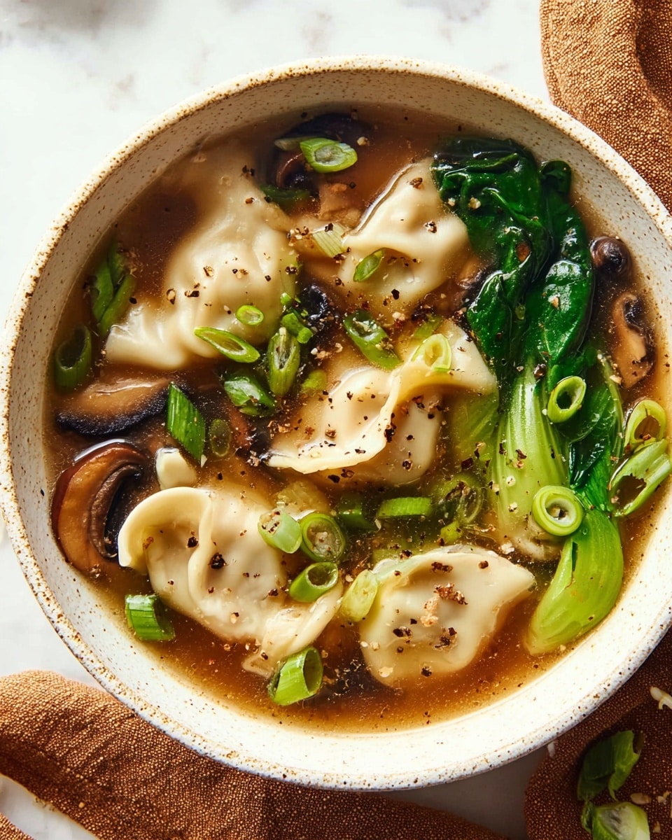 A white bowl filled with a clear brown broth containing several pale, folded dumplings that have soft, smooth texture showing folds. There are dark brown mushroom slices and bright green leafy vegetables floating on one side. Scattered across the surface are small ringed slices of light green and bright green scallions, adding a fresh pop of color. Tiny specks of black pepper are sprinkled over the dumplings and broth, giving a slightly speckled appearance. The background is a white marbled surface with a brown cloth napkin partially visible. photo taken with an iphone --ar 4:5 --v 7