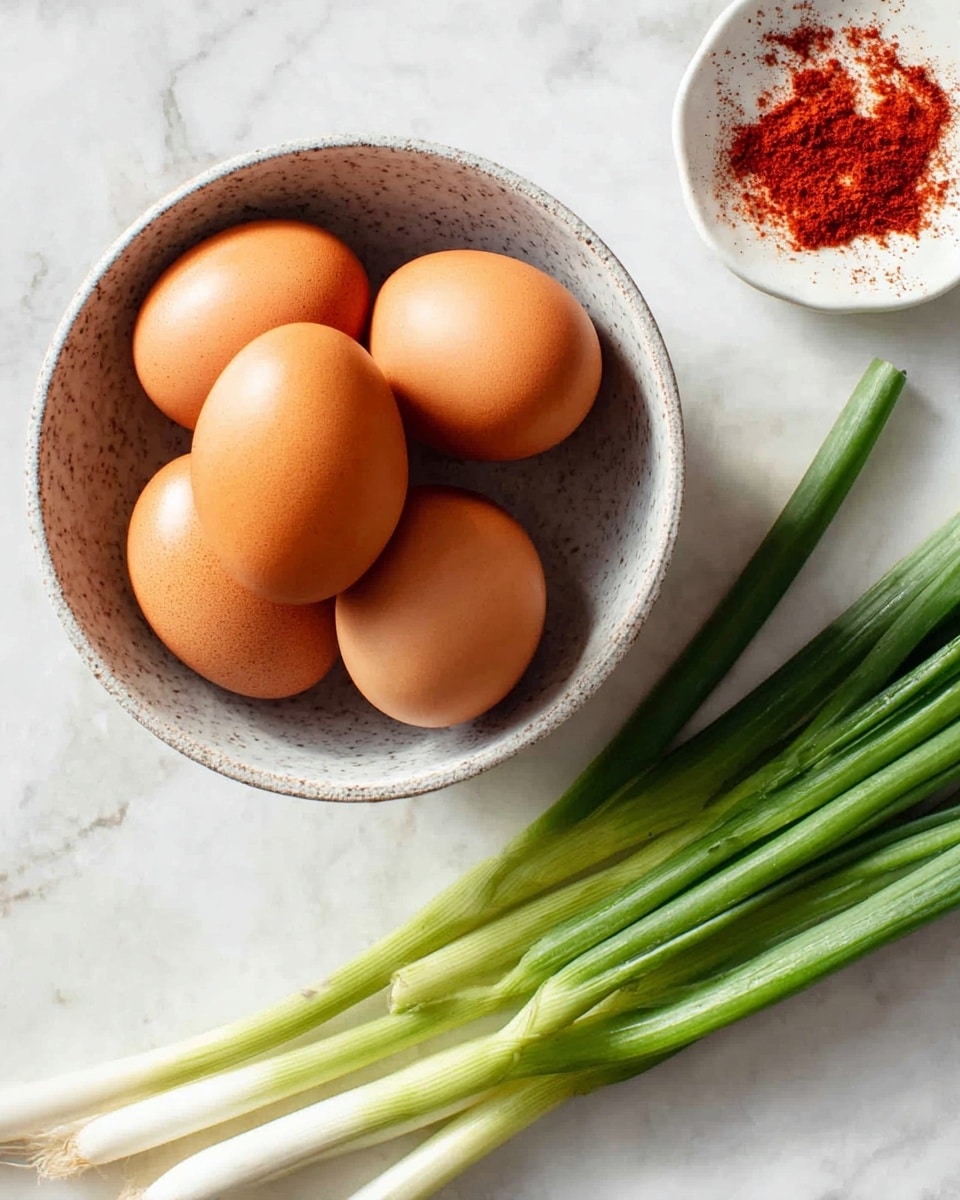 A round bowl with a speckled light gray inside holds five smooth brown eggs stacked gently, with three at the bottom and two resting on top. To the right of the bowl, several fresh green onions with white bulbs lay side by side, their long green stalks extending upward. In the top right corner, there is a small white dish with red powder on it. All items rest on a white marbled surface that gives a clean and bright look. Photo taken with an iphone --ar 4:5 --v 7