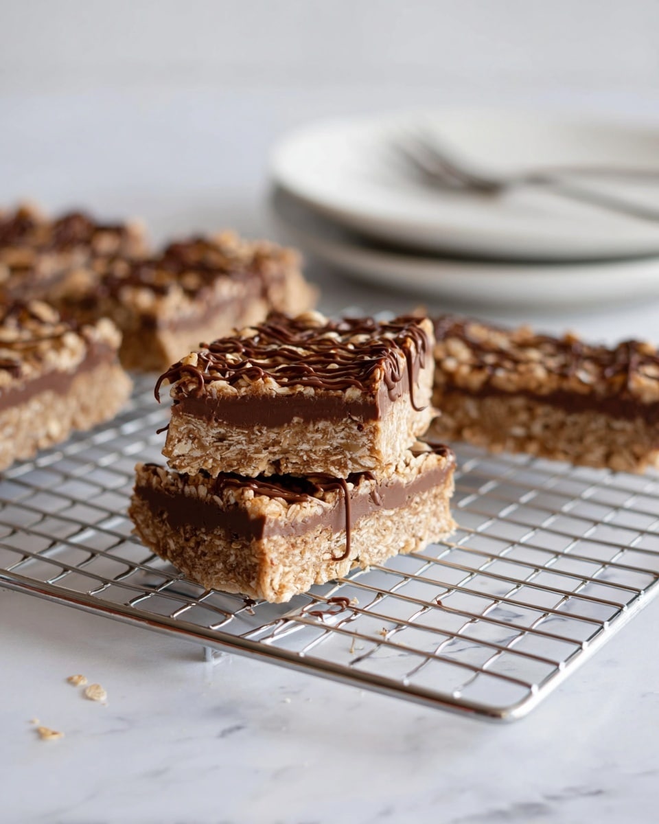 The image shows a stack of two thick granola bars on a silver cooling rack, in the front right of the image. Each bar has three visible layers: a bottom chocolate layer that is smooth and dark brown, a thick middle layer of light tan oats with a coarse texture, and a top layer with drizzled chocolate over the oats. In the background, there are four more granola bars lying on the cooling rack, with a white plate and a fork softly out of focus behind them. The whole scene sits on a white marbled surface. photo taken with an iphone --ar 4:5 --v 7