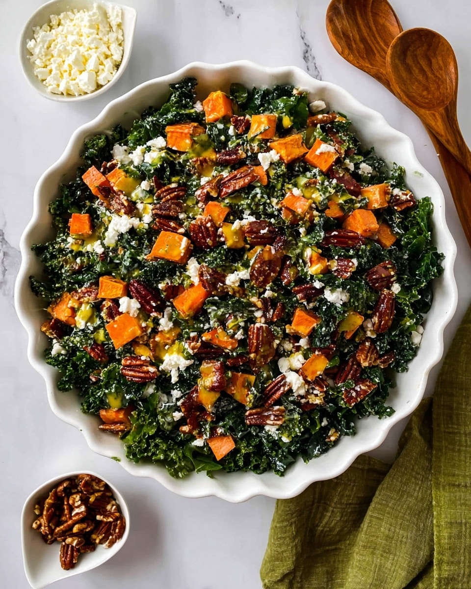 A white scalloped bowl is filled with a colorful kale salad featuring deep green kale leaves as the base layer. On top, there are bright orange chunks of roasted sweet potatoes mixed evenly with crunchy, dark brown pecan halves. White crumbles of cheese are scattered throughout, adding texture and contrast. A light yellow dressing is drizzled across the salad, giving a glossy finish. To the sides of the bowl, small white dishes hold extra cheese and pecans. The bowl sits on a white marbled surface with two wooden salad spoons resting nearby alongside a green cloth. photo taken with an iphone --ar 4:5 --v 7