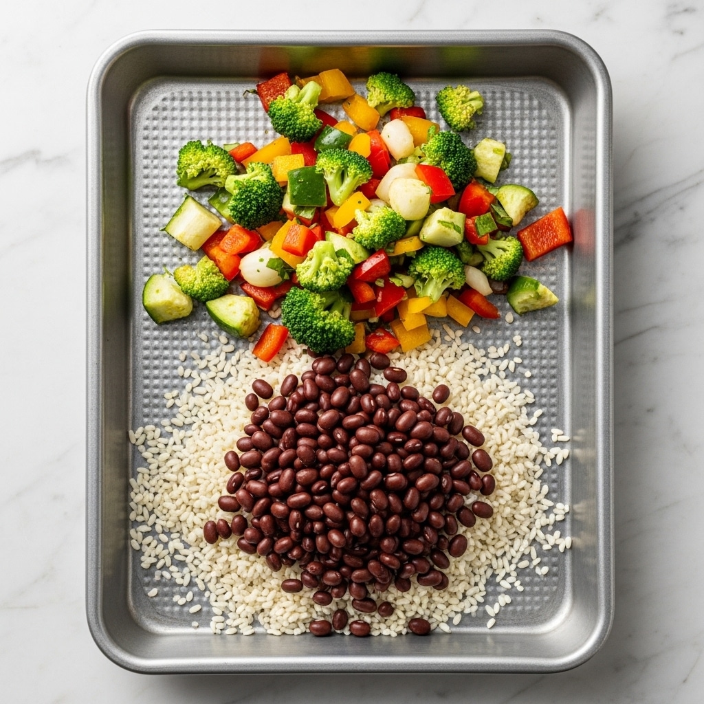 Inside a silver baking pan with a patterned texture, there are three layers of ingredients. The bottom layer is white rice scattered unevenly across the base. On top of the rice, on the lower right side, there is a pile of dark brown small beans that cover part of the rice. The top layer is a mix of chopped vegetables, including bright green, red, yellow, and white pieces, scattered mainly on the upper side and overlapping slightly with the beans and rice. The pan sits on a white marbled texture surface. Photo taken with an iphone --ar 4:5 --v 7