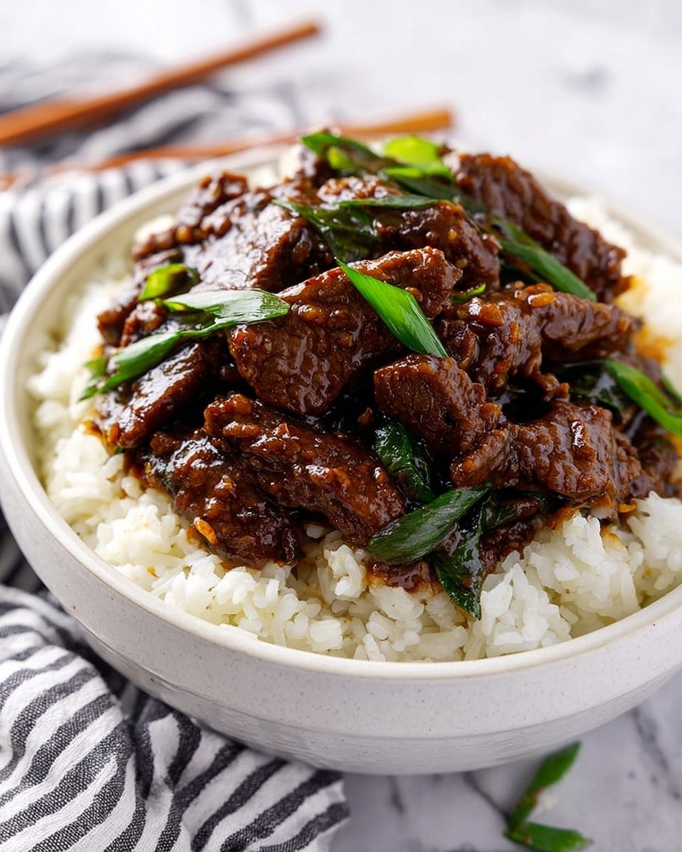A white bowl filled with a base layer of fluffy white rice, topped with a generous serving of dark brown beef strips coated in a shiny, thick sauce, mixed with scattered fresh green scallion pieces. The rice grains are clearly visible beneath the beef, creating a nice contrast in texture and color. The bowl sits on a white marbled surface with a striped cloth and chopsticks blurred in the background. photo taken with an iphone --ar 4:5 --v 7