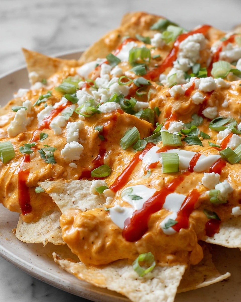 The image shows a close-up of a plate layered with crispy light beige tortilla chips at the bottom, covered with a thick layer of creamy orange cheese sauce that has a rich and smooth texture. Scattered on top are small white cheese crumbles and fresh green chopped scallions, adding a pop of color. Drizzled over the dish are thin lines of white sour cream and bright red hot sauce, both adding contrast and extra flavor. The chips are lightly folded and overlapping, creating depth and texture in the image. The dish is set on a white marbled surface. photo taken with an iphone --ar 4:5 --v 7