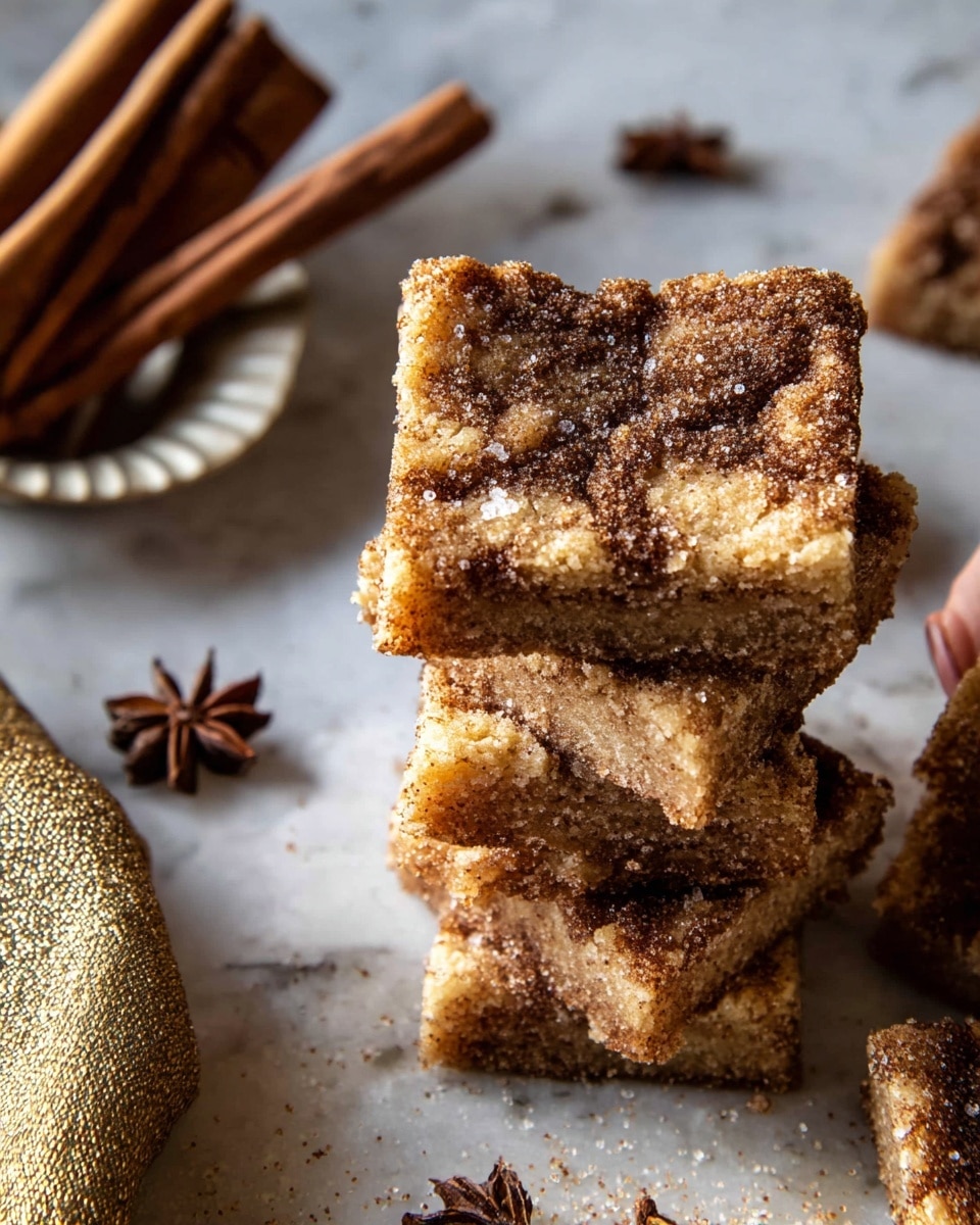 The image shows a stack of seven square cinnamon sugar bars with a crumbly texture on top. The top bar has a golden brown surface with darker cinnamon swirls mixed in, and a layer of sugar crystals sparkling over it. The other bars underneath have similar textures and colors, slightly shaded due to stacking. To the left side, there is a small white plate holding a bundle of cinnamon sticks, with a woman's hand partially covered by a gold textured cloth holding the plate. The background is a white marbled surface with a few star anise scattered around. The whole scene has warm tones and a cozy, rustic feel. photo taken with an iphone --ar 4:5 --v 7