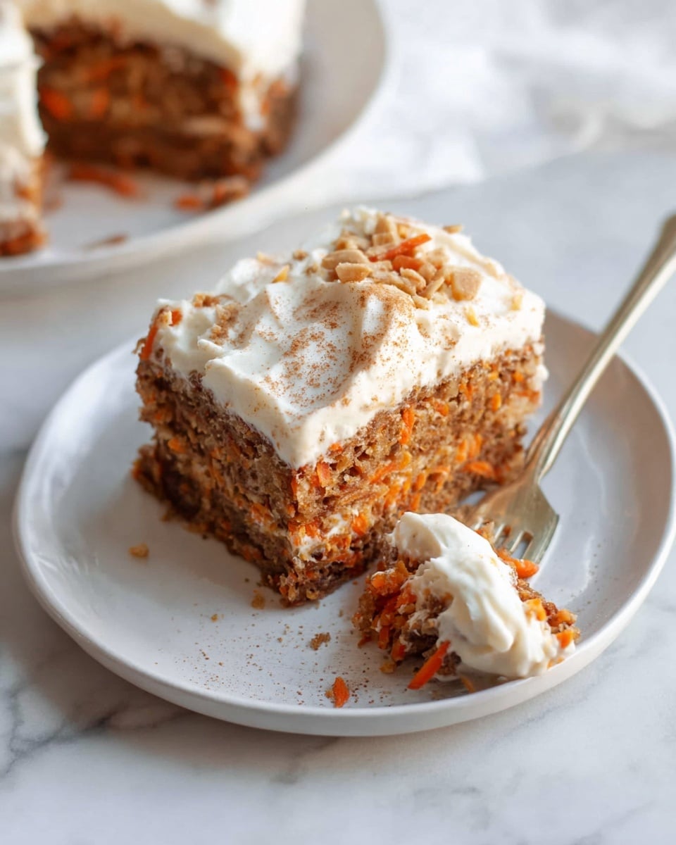 A square slice of oatmeal carrot cake sits on a white plate, showing two main layers: a dense, moist brown layer filled with small orange carrot pieces and oats at the bottom, topped by a thick, fluffy white layer of creamy frosting sprinkled with a light dusting of cinnamon. In front of the slice, a fork holds a smaller bite of the same brown cake, revealing the moist texture and orange carrot bits inside. The setting is on a white marbled surface with soft natural lighting. photo taken with an iphone --ar 4:5 --v 7