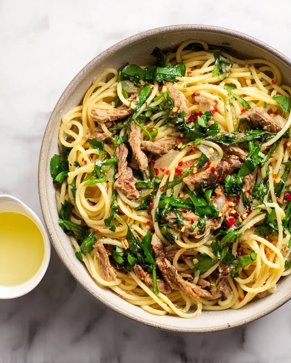 A bowl filled with spaghetti layered with tender pieces of cooked meat, scattered fresh green leafy herbs, and small bits of red chili flakes visible among the noodles. The spaghetti is a pale yellow color, while the herbs are bright green and add a fresh look. The meat strips are light brown, mixed evenly throughout the pasta. This bowl sits on a white marbled surface with a small white cup of light yellow liquid nearby. photo taken with an iphone --ar 4:5 --v 7