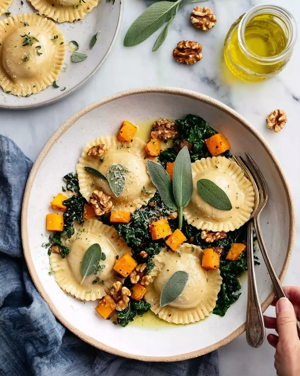 A white shallow bowl holds four large, round ravioli with crimped edges, arranged in the center. Beneath and around the ravioli are dark green cooked leafy vegetables, likely kale or spinach, adding texture and deep green color. Small orange cubes of roasted butternut squash are scattered evenly over the ravioli and greens, giving a bright contrast. A few brown walnut pieces are also spread over the dish, adding a crunchy element. Each ravioli is topped with a single fresh green sage leaf, enhancing the presentation. Behind the bowl, part of another white plate with similar ravioli and a fork are visible. The scene is set on a white marbled surface with a jar of yellow oil, scattered walnuts, fresh herbs, and a blue cloth napkin. A woman’s hand reaches from the bottom right, holding a fork. photo taken with an iphone --ar 4:5 --v 7