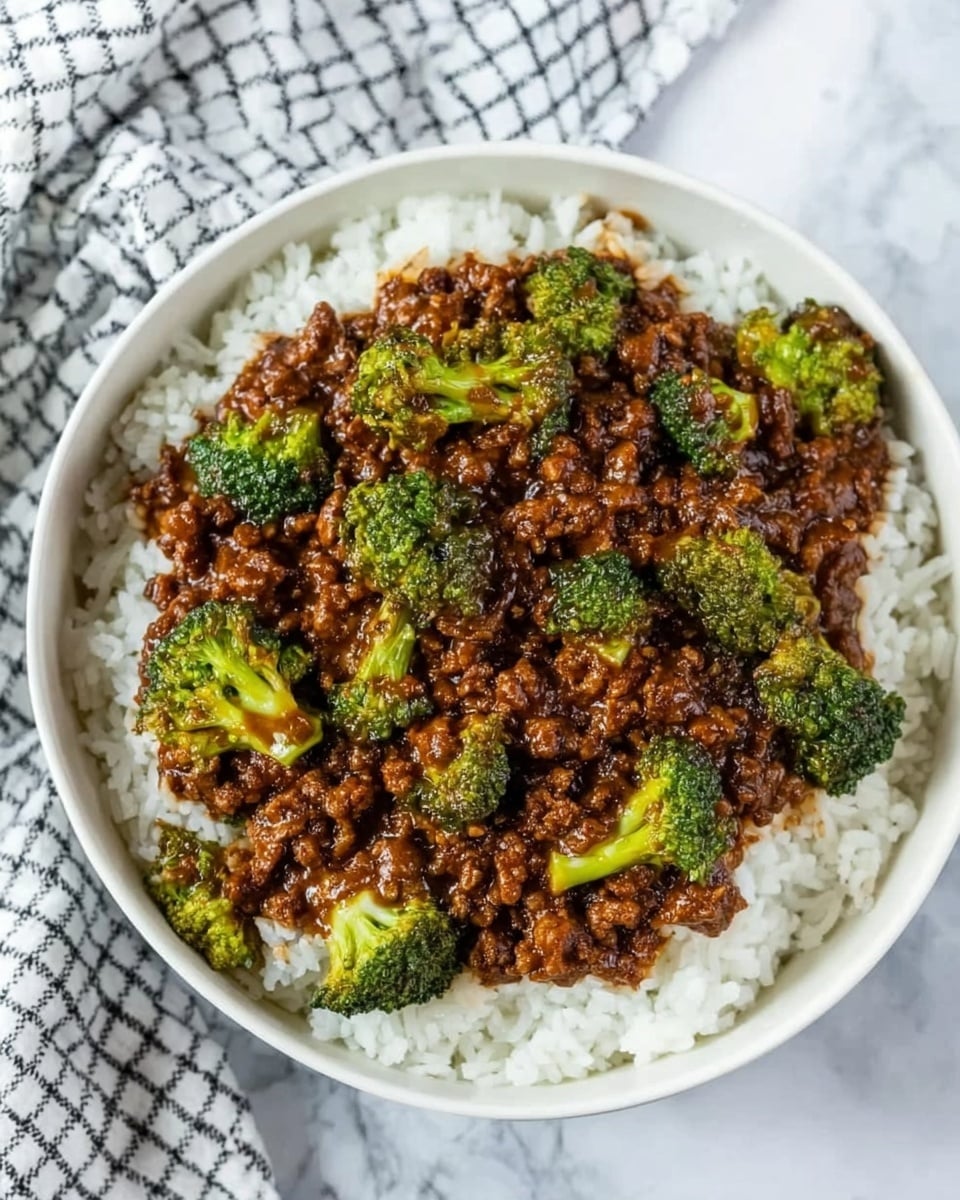 A white bowl filled with a base layer of plain white rice, topped with a thick layer of dark brown sauce mixed with small pieces of ground meat and bright green broccoli florets scattered evenly across the surface. The bowl is placed on a white marbled surface next to a white and black checkered cloth. The textures show fluffy rice underneath and a rich, chunky sauce above with the broccoli adding pops of green color. Photo taken with an iphone --ar 4:5 --v 7