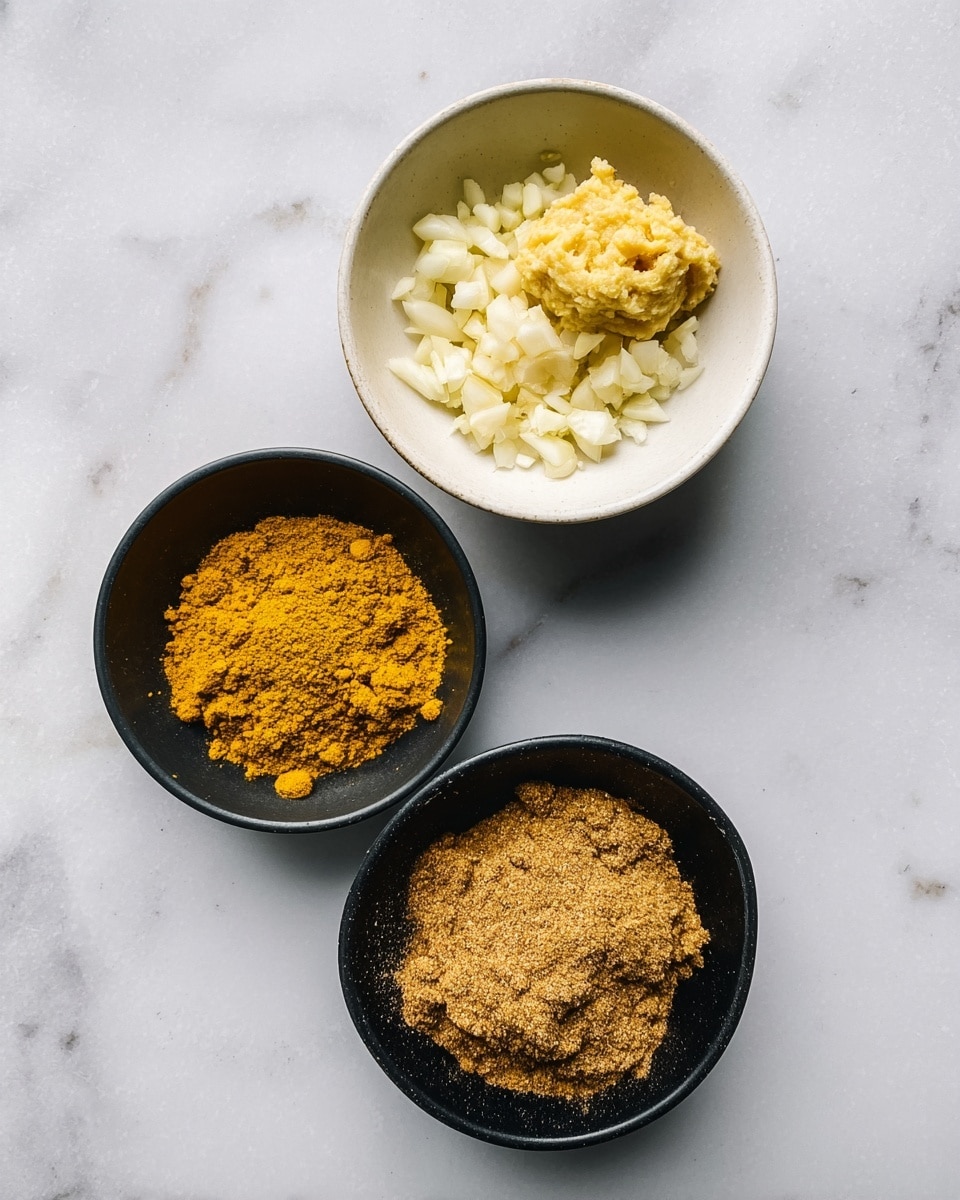 Three bowls are placed on a white marbled surface. The top white bowl holds chopped white garlic and a small mound of pale yellow paste, placed next to each other inside the bowl. Below, two black bowls sit with different spices; the upper one contains two spices side by side bright yellow turmeric on the right and a light brown spice on the left, while the lower black bowl is filled fully with a medium brownish-yellow spice powder. The arrangement is neat and the spices show fine textures. Photo taken with an iphone --ar 4:5 --v 7