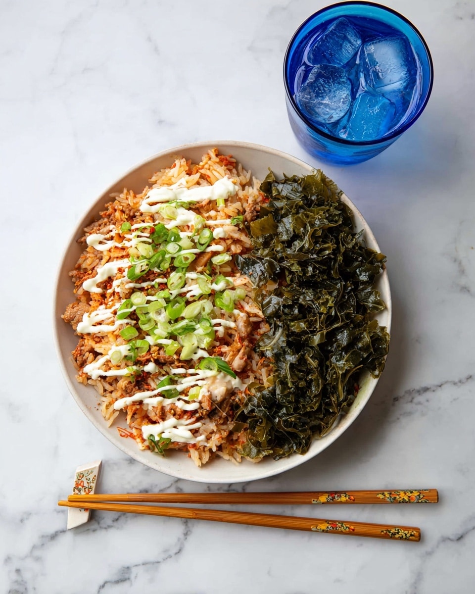 In a white bowl on a white marbled surface, there is a dish with two main parts: one side has a mix of white and orange rice with small pieces of light brown meat, topped with thin lines of creamy white sauce and scattered green onion slices, while the other side has dark green baked leafy vegetables with a wrinkled texture. Below the bowl, on the surface, are a pair of wooden chopsticks with light beige decorated tips. To the top right of the bowl, there is a blue glass filled with ice and water. Photo taken with an iphone --ar 4:5 --v 7