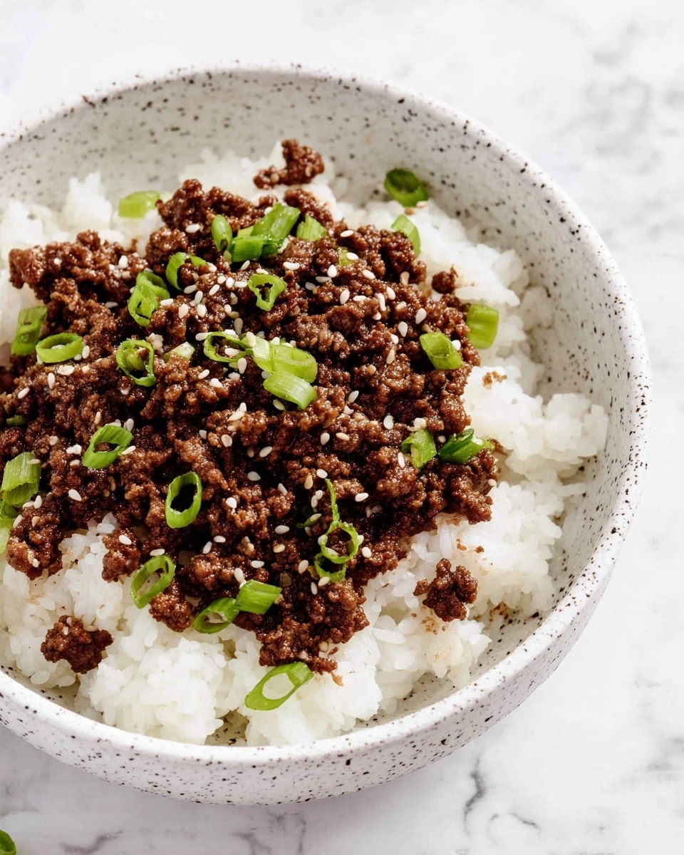 A bowl with two layers sits on a white marbled surface: the bottom layer is soft, fluffy white rice, and the top layer is cooked ground meat, dark brown in color with a slightly textured surface. Scattered on top are small pieces of chopped green onions and white sesame seeds, adding pops of green and white to the rich brown meat. The bowl itself is white with grey speckles. photo taken with an iphone --ar 4:5 --v 7