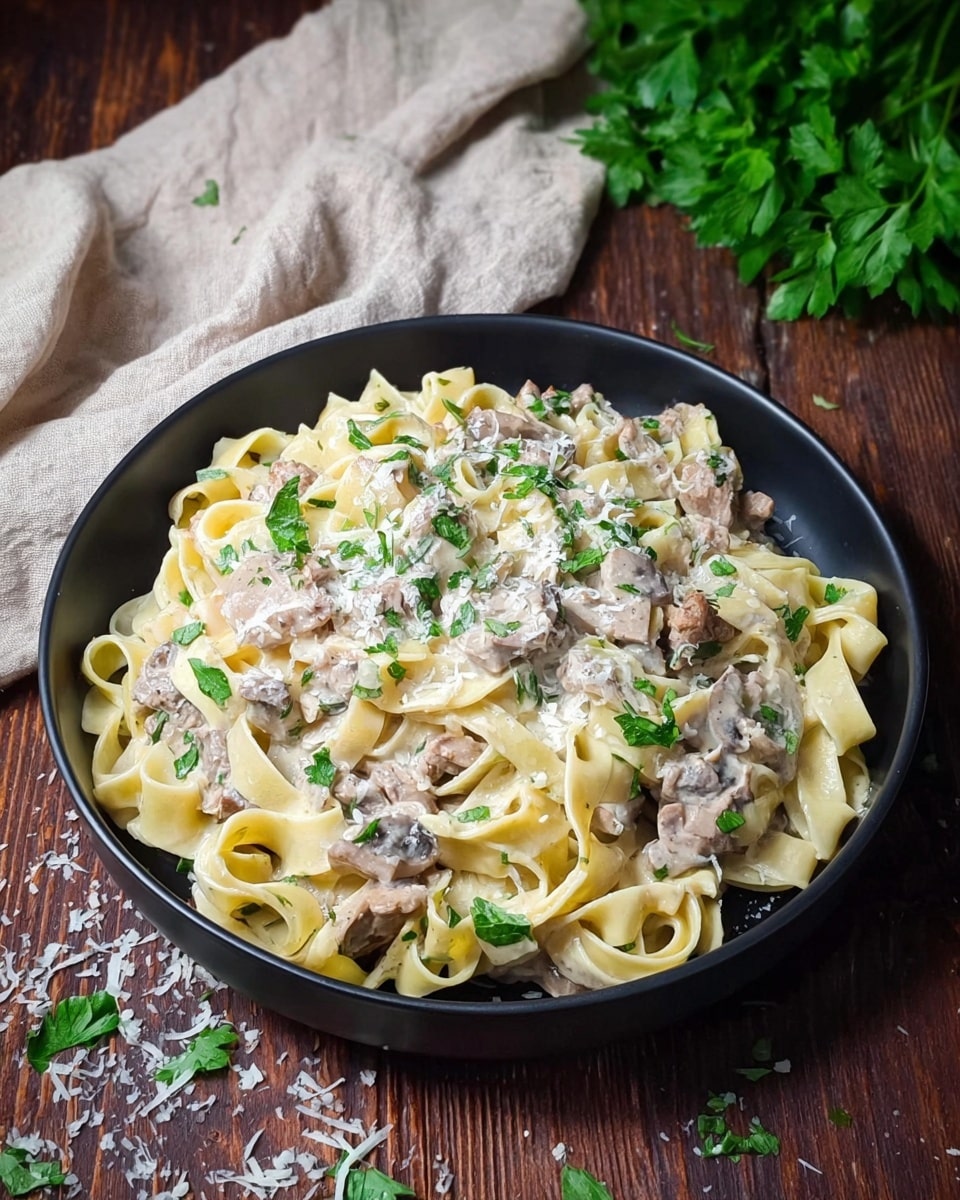 A black bowl filled with creamy pasta made of several layers of pale yellow fettuccine noodles, mixed with small pieces of light brown cooked meat and sliced mushrooms, all covered in a white creamy sauce dotted with fresh green parsley leaves. The dish is topped with grated white cheese scattered both on the pasta and around the bowl on a wooden surface. A beige cloth is casually placed in the background alongside green parsley leaves on the right. Photo taken with an iphone --ar 4:5 --v 7