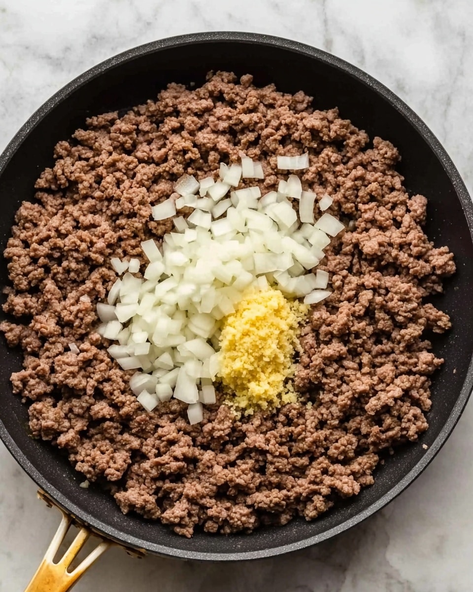 A black frying pan on a white marbled surface holds cooked ground beef that covers the bottom evenly. On top of the beef, there is a pile of finely chopped white onions in the center and a small mound of yellow minced garlic placed near the onions. The beef is brown and crumbly, the onions look fresh and crisp, and the garlic appears moist and slightly textured. The pan has a gold handle facing downwards. photo taken with an iphone --ar 4:5 --v 7