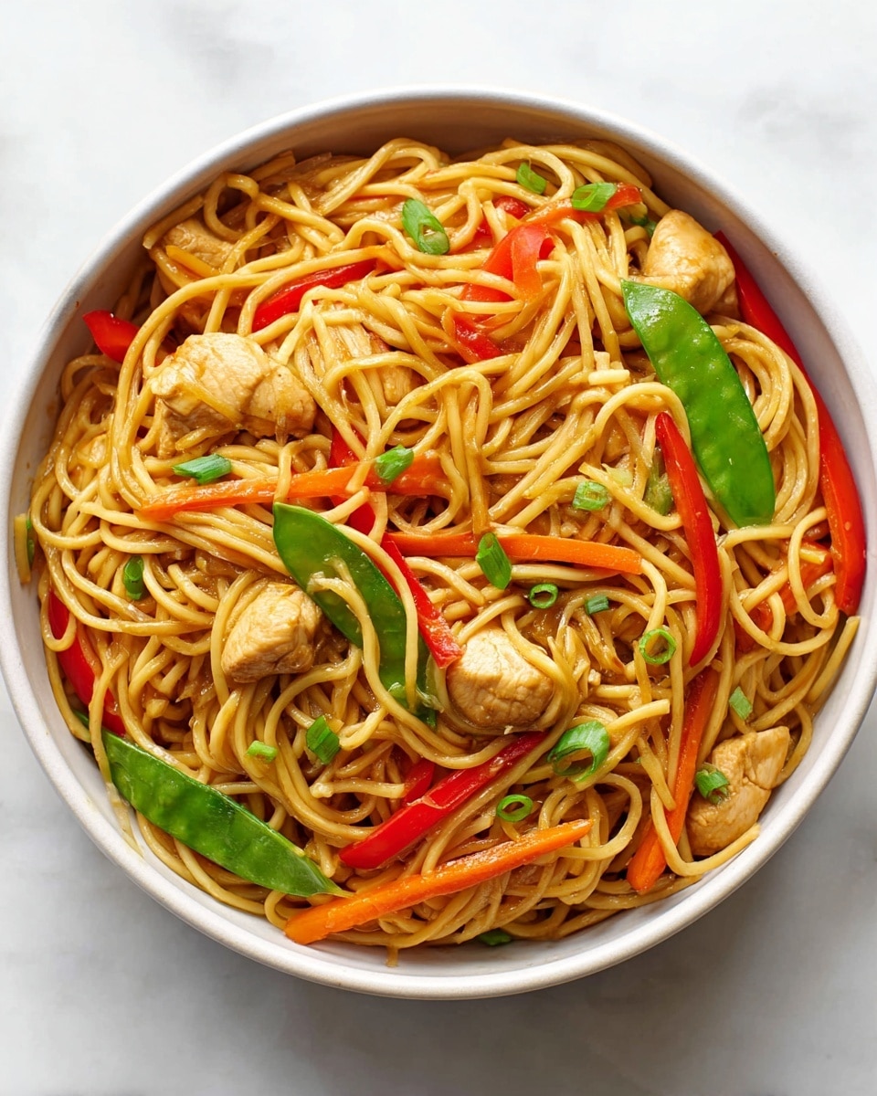 A white bowl filled with stir-fried noodles as the bottom layer, light brown and slightly glossy, mixed with small pieces of light tan cooked chicken scattered throughout. Among the noodles are bright, colorful vegetables including thin, long strips of orange carrots, red bell pepper slices, and vibrant green snow peas. Small pieces of chopped green onions are sprinkled on top. The bowl sits on a white marbled textured surface. Photo taken with an iphone --ar 4:5 --v 7