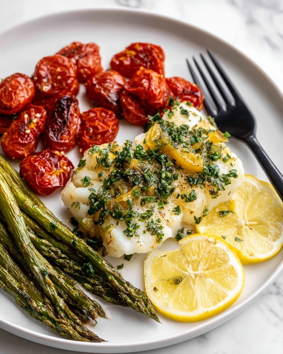 The image shows a white plate with a serving of white fish topped with green herbs and small pieces of lemon slices placed around it. To the left side of the fish, there is a pile of roasted cherry tomatoes with a wrinkled, shiny red texture. Below the fish, there are several roasted green asparagus stalks lying in a bundle. A black fork is resting on the right side of the plate, partially on the fish. The plate is set on a white marbled surface. The photo taken with an iphone --ar 4:5 --v 7