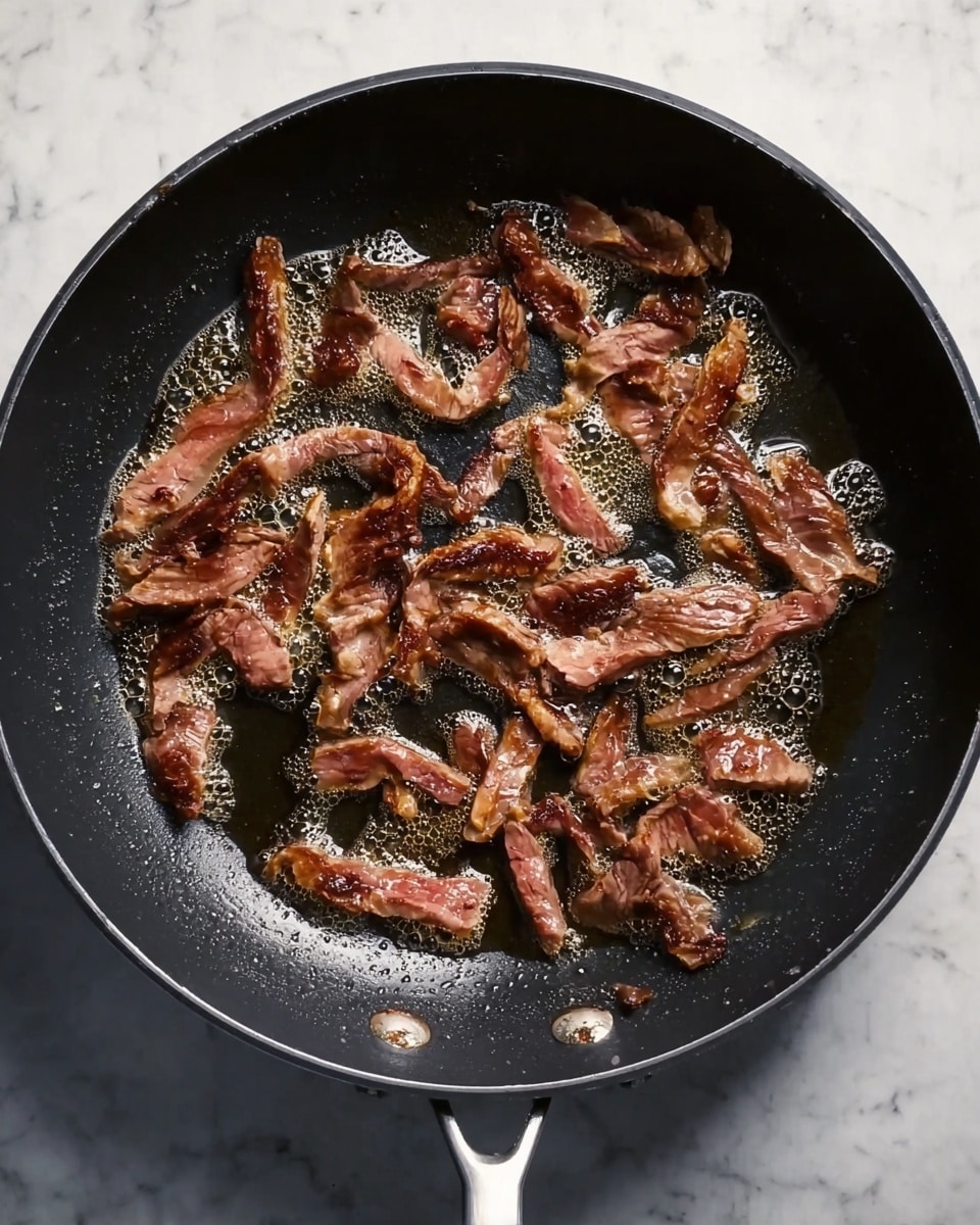 Inside a black frying pan with white handles, many small strips of brown meat are spread out unevenly, showing some parts still pinkish as they cook in a thin layer of bubbling oil. The pan is placed on a white marbled surface, giving contrast to the dark pan and warm tones of the meat while the light reflects off the shiny oil bubbles. photo taken with an iphone --ar 4:5 --v 7