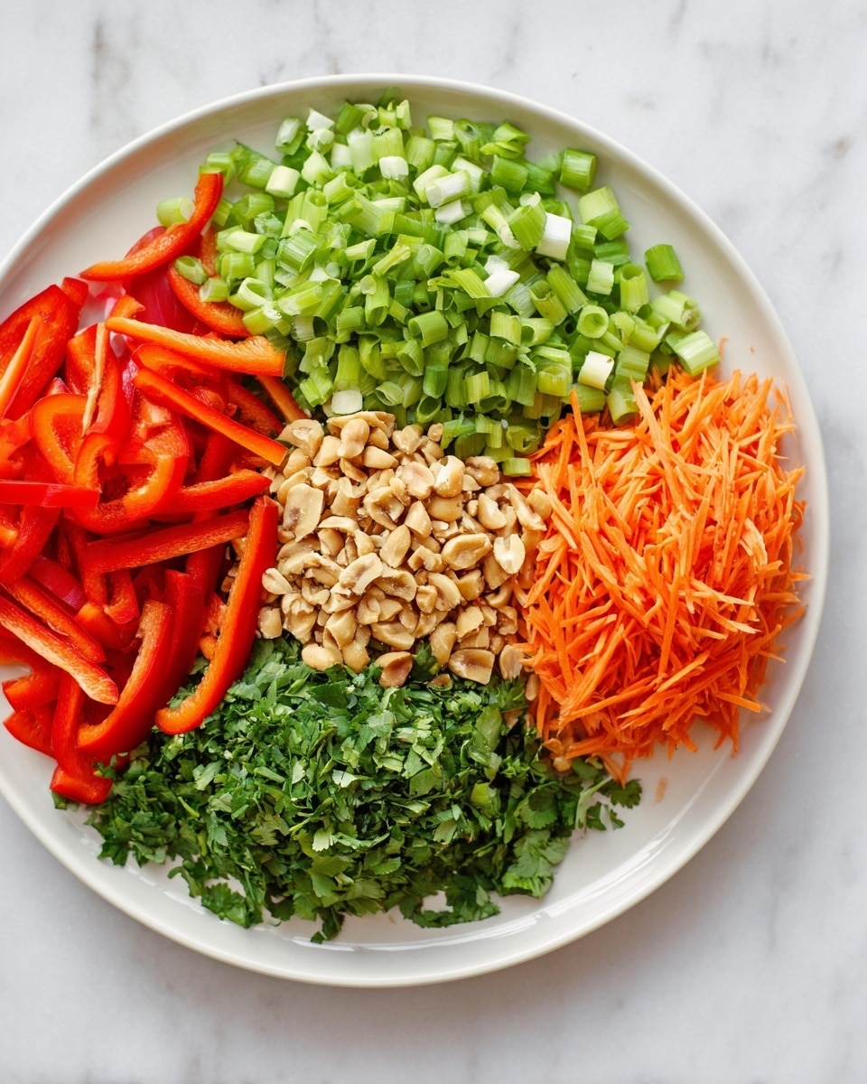 A white plate holds five neatly arranged groups of chopped vegetables and nuts, each taking about a fifth of the space in a circular layout. Starting from the top left, bright green chopped green onions form a fresh, slightly chunky layer. To the right of them, there is a pile of thin orange carrot strips standing upright, adding a fine, stringy texture. Moving clockwise, a pile of roughly chopped light brown nuts sits, showing a mix of smooth and rough textures. Below the nuts, fresh and finely chopped green herbs sit in a dense mound. Finally, at the bottom left of the plate, sliced red bell pepper strips with a slightly glossy surface complete the circle. The plate rests on a white marbled textured surface. photo taken with an iphone --ar 4:5 --v 7