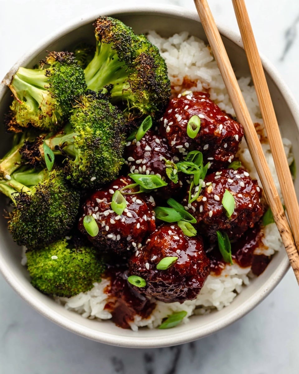 A bowl with three layers is shown: the bottom layer is white rice with a soft texture, the middle layer has shiny, dark red meatballs covered in a sticky sauce, sprinkled with white sesame seeds and chopped green onions, and the top layer has bright green broccoli with some charred edges. A pair of wooden chopsticks rests on the rice near the broccoli. The bowl is white, placed on a white marbled surface. Photo taken with an iphone --ar 4:5 --v 7