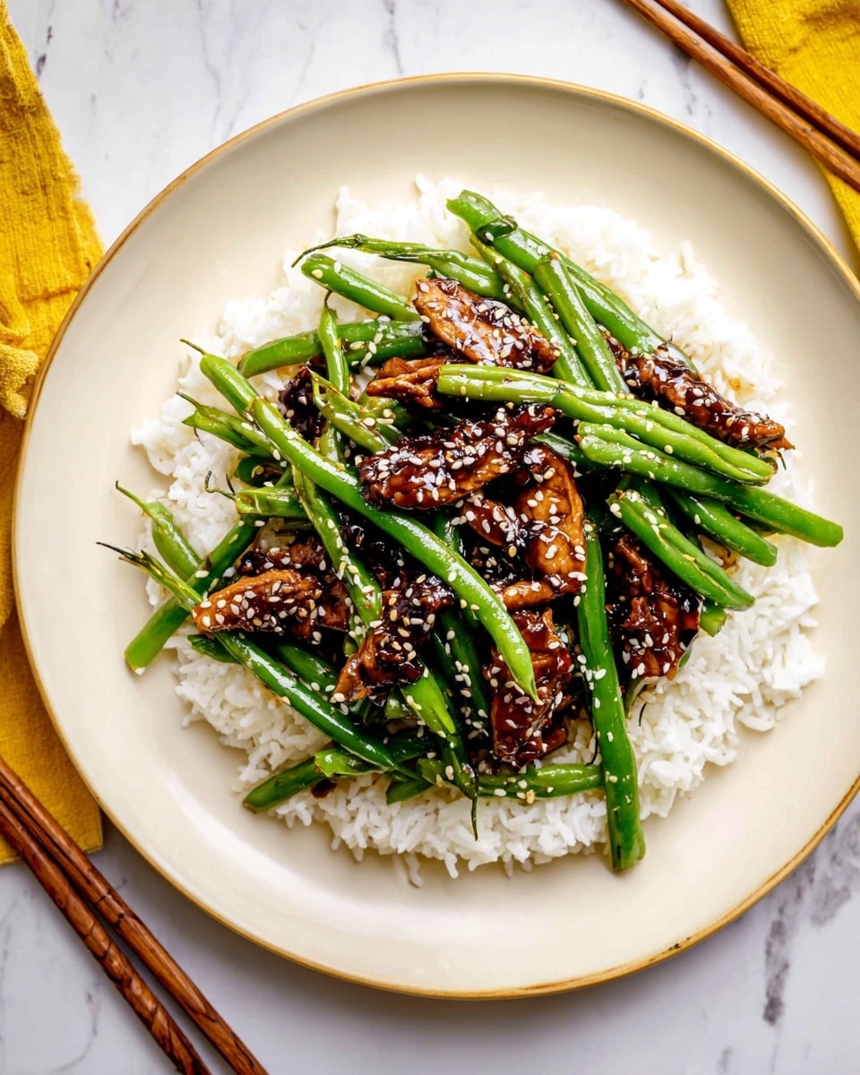 A white round plate holds a dish with three layers. The bottom layer is fluffy white rice, spread evenly over the plate. The middle layer consists of long, bright green cooked green beans placed over the rice. The top layer features dark brown glazed pieces of cooked chicken scattered on the green beans. The dish is sprinkled with small white sesame seeds. The plate sits on a white marbled surface, with a pair of chopsticks nearby. Photo taken with an iphone --ar 4:5 --v 7