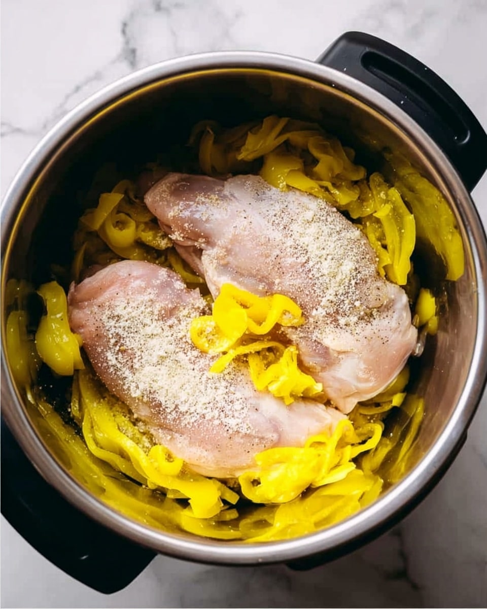 Inside a silver cooking pot with black handles, there are two raw chicken pieces placed side by side, with a light sprinkle of white powder seasoning on top. Around the chicken, bright yellow pickled peppers are spread evenly, filling the space between and around the chicken. The pot sits on a white marbled surface. Photo taken with an iphone --ar 4:5 --v 7