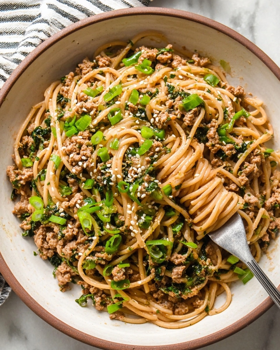 A white bowl with a brown rim filled with a mixed layer of light brown cooked spaghetti noodles intertwined with small pieces of cooked ground meat, bright green sliced scallions scattered on top, and white sesame seeds sprinkled throughout. The noodles and meat have a glossy, slightly oily texture, with finely chopped dark green herbs mixed in. A silver fork is twirling some noodles on the right side of the bowl. The bowl is placed on a white marbled surface with a striped cloth partially visible in the top left corner. photo taken with an iphone --ar 4:5 --v 7