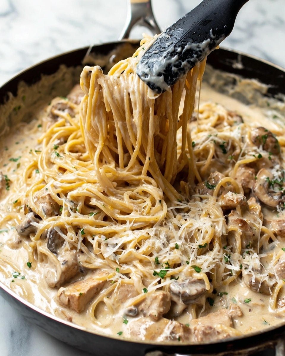 A close-up of a pan filled with creamy pasta layers, the bottom layer is a thick, light beige sauce with small green herbs sprinkled. On top, there are long, thin spaghetti noodles, also coated in the creamy sauce, light beige with a soft shiny texture. Mixed in the pasta are chunks of light brown meat and pieces of brown mushrooms, giving a mixed texture. A black spatula is lifting a twisted bunch of noodles in the center, showing the smooth cream sauce dripping slightly. The pan sits on a white marbled surface. photo taken with an iphone --ar 4:5 --v 7