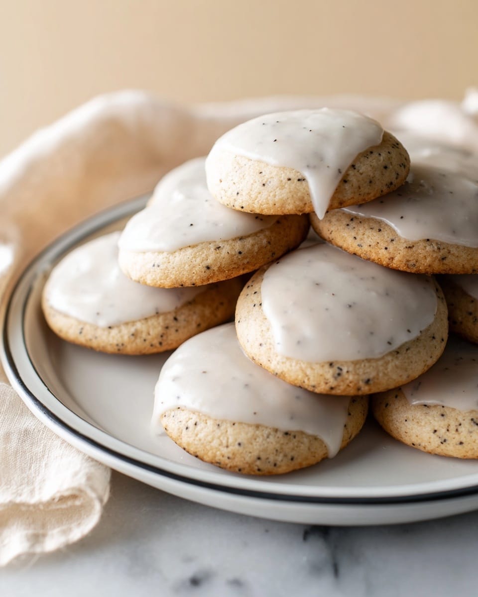 A pile of round cookies with light brown color and small dark specks, each topped with a smooth layer of white glaze that slightly drips at edges, all stacked on a white plate with a thin black rim, resting on a white marbled surface with a soft beige cloth partially visible to the side photo taken with an iphone --ar 4:5 --v 7