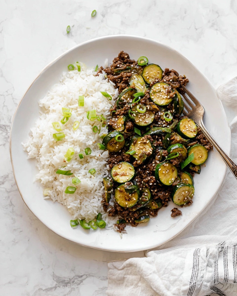 A white plate sits on a white marbled surface, filled with two main layers: on one side, there is a mound of white rice with a fluffy texture, and on the other side, a mix of dark brown ground meat and light green cooked zucchini slices scattered with small white sesame seeds and bright green chopped scallions. There is a silver fork resting partially in the rice, curving gently towards the edge of the plate. A white cloth with thin gray stripes is partially visible near the bottom right corner of the image. Photo taken with an iphone --ar 4:5 --v 7