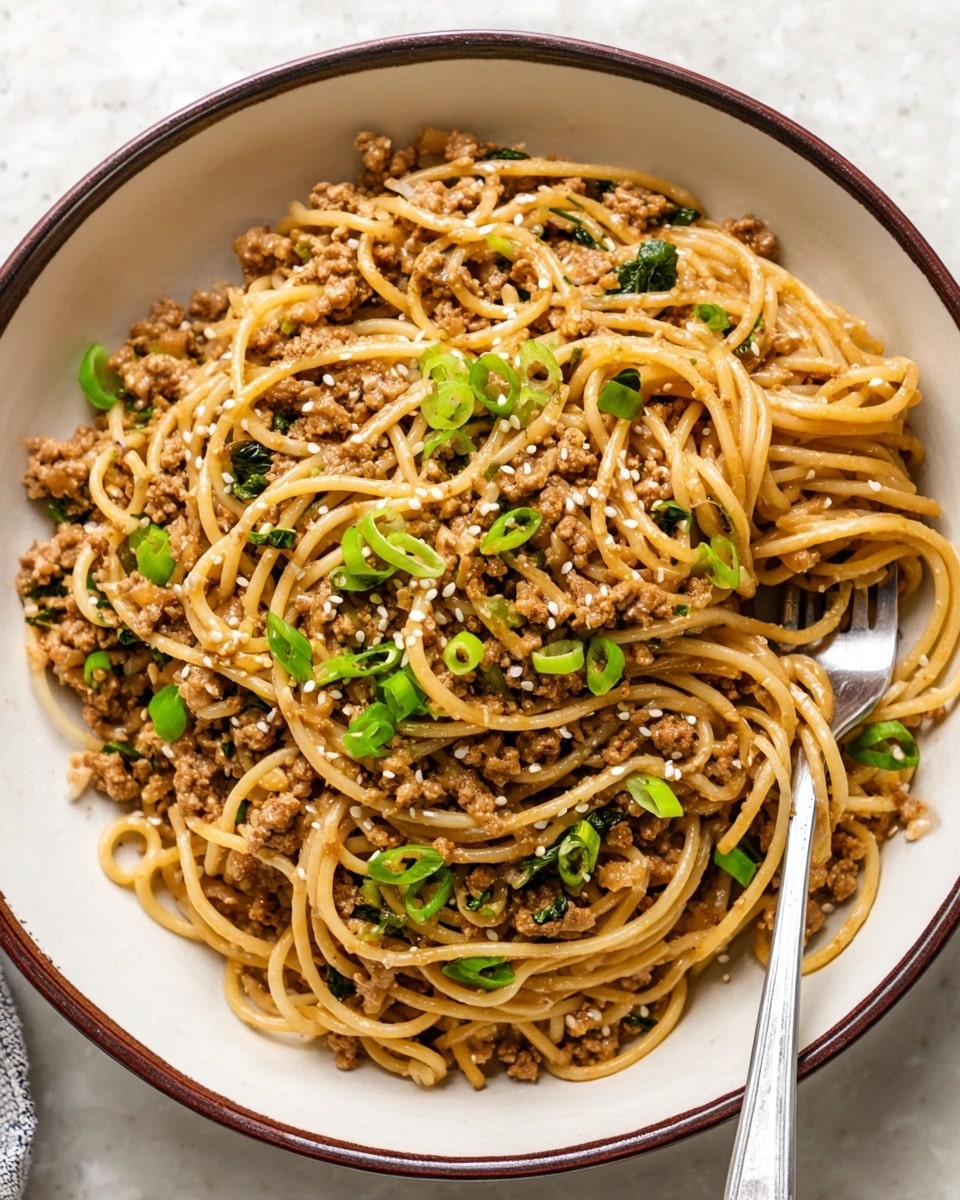 A bowl filled with spaghetti noodles mixed with small pieces of cooked ground meat, evenly distributed among the noodles. The noodles are light brown with a slightly glossy texture, coated in a savory sauce. Small green onion slices are sprinkled on top, adding bright green color. White sesame seeds are also scattered over the dish. A silver fork rests on the right side of the bowl, slightly lifting some noodles. The bowl is white with a thin dark brown rim, placed on a white marbled surface. photo taken with an iphone --ar 4:5 --v 7