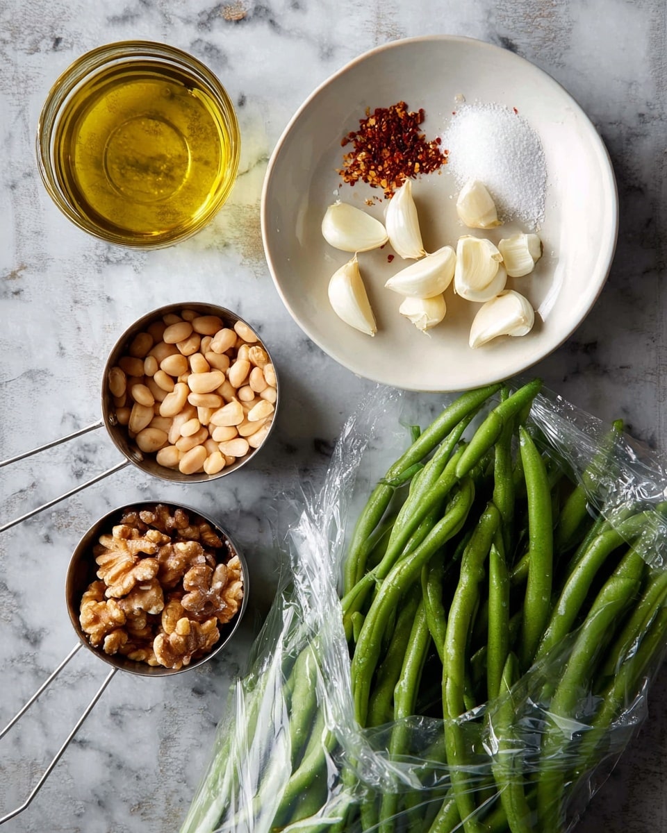 A white shallow bowl holds peeled garlic cloves, red chili flakes, and a pile of white salt, arranged in neat small piles in the upper half. Below and to the left, a clear glass cup contains golden olive oil with light reflections. Two metal measuring cups sit side by side in the lower left: the left one is filled with small beige beans, and the right one holds walnut halves. On the right side, a clear plastic bag is open, filled with fresh, green beans that are long and firm. All items are placed on a white marbled surface with subtle veins and light texture, viewed from above. photo taken with an iphone --ar 4:5 --v 7